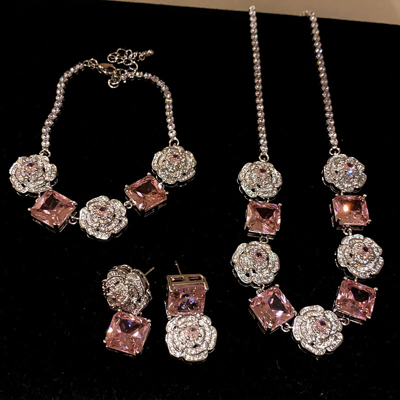 Conjunto de anillo, pendientes y collar con diseño de rosas rosas, decorado con circonitas cúbicas en estilo delicado y lujoso, transmitiendo una sensación de elegancia y alta gama.